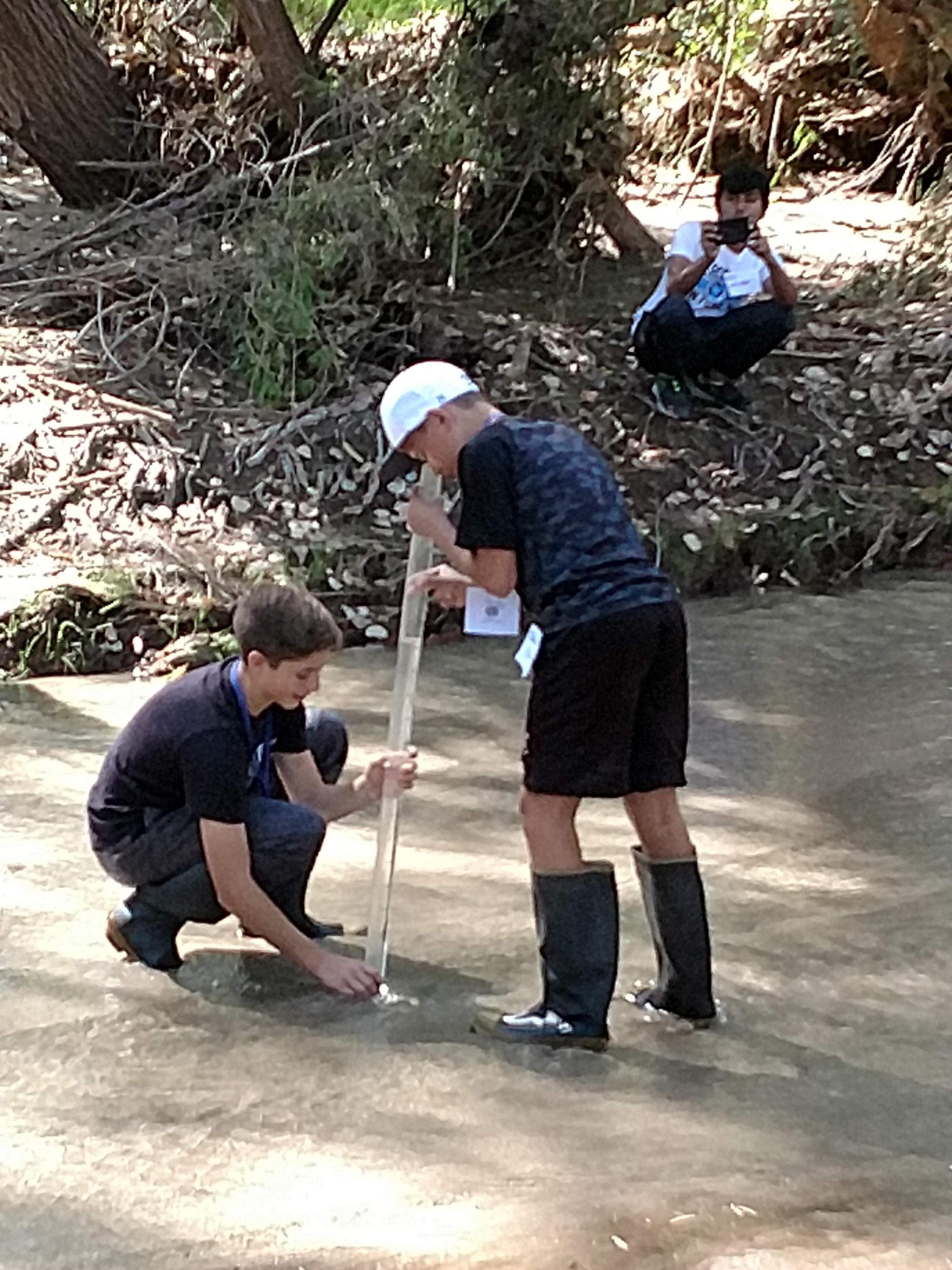 photo of students using a tool in the river.